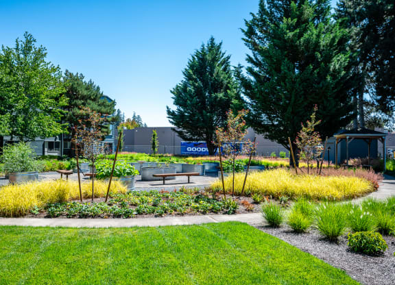 a garden with benches and trees in front of a building