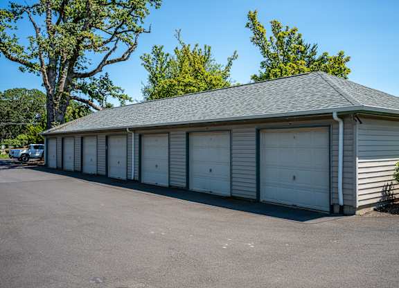 A long building with a grey roof and white garage doors.