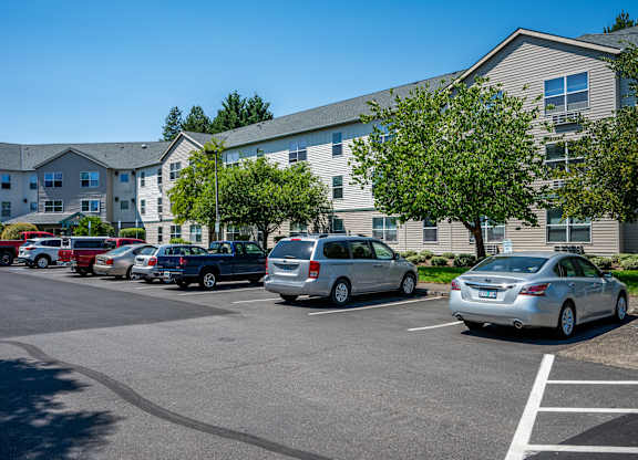 A parking lot with cars and a building in the background.