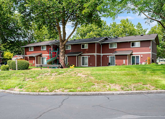 A red brick apartment building with a green lawn in front.