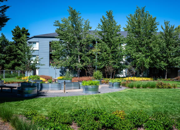 a garden with benches and trees in front of a building