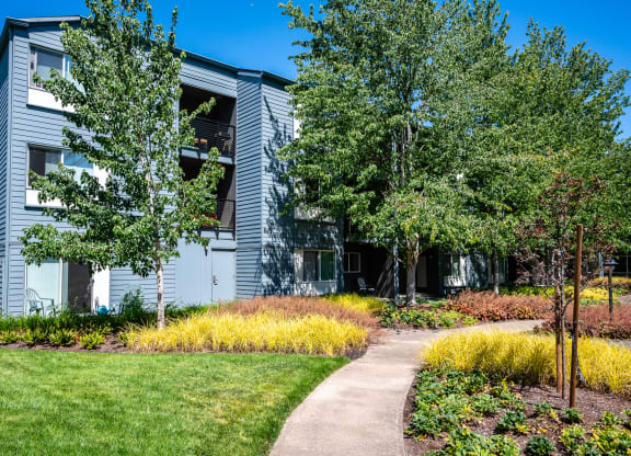a sidewalk in front of a building with trees