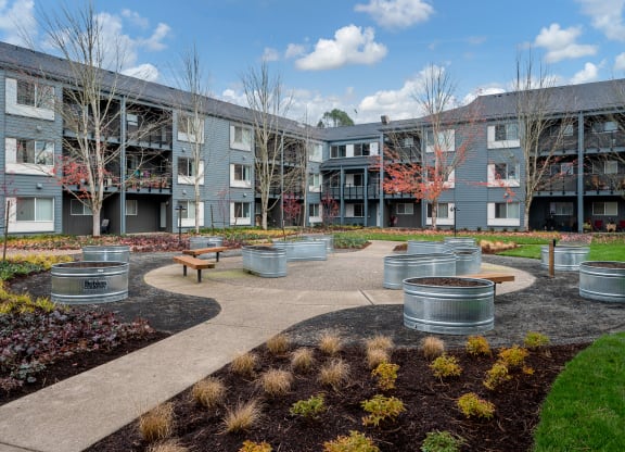 a courtyard with benches and trees in front of an apartment building