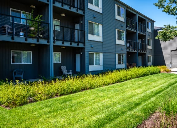 a row of apartment buildings with green grass and yellow flowers
