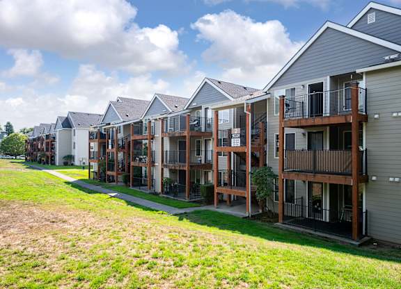 A row of houses with balconies and a green lawn in front.