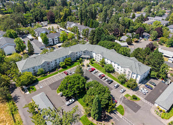 A large white building surrounded by trees and a parking lot.