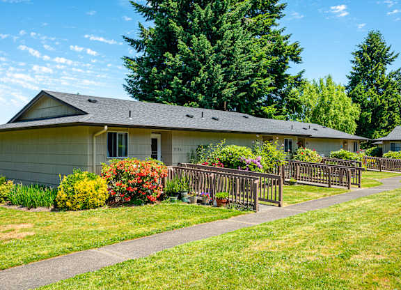 A house with a grey roof and a green lawn in front.