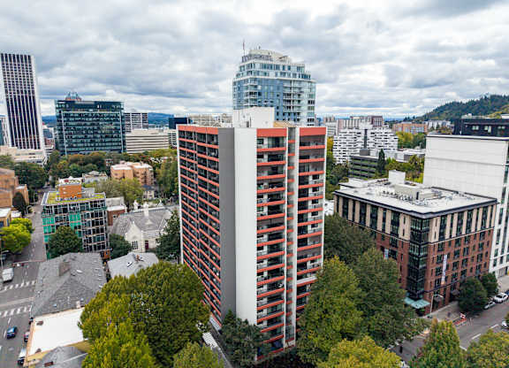 A tall red and white building stands in the middle of a city.