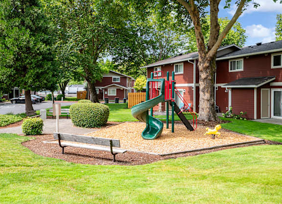 A playground with a green slide and a yellow duck in the foreground.