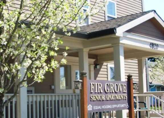 A tree with white flowers is in front of a building with a sign that says Fir Grove Senior Apartments.