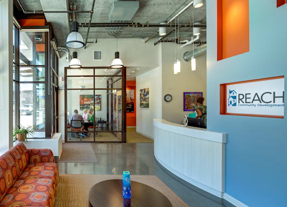 A brightly lit office space with a reception desk and a sofa.