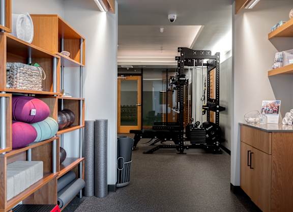 A room with a gym equipment set up and a shelf with various items.