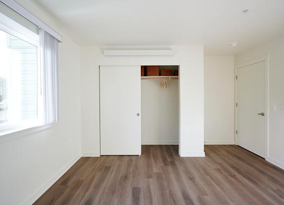 A room with a white door and a window with white curtains.