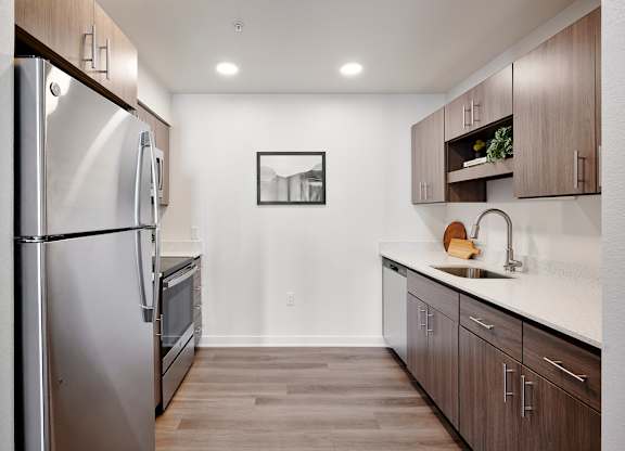 A modern kitchen with a refrigerator, oven, and sink.