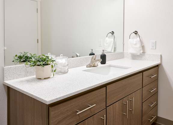 A bathroom with a white countertop and brown cabinets.