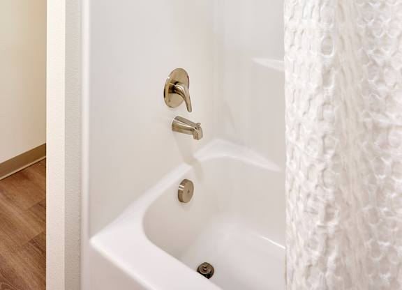 A white bathroom with a white tub and a white shower curtain.