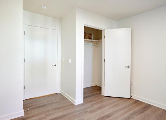 Three white doors in a room with wood floors.