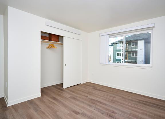 A room with a white door and a window showing a building outside.