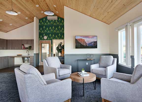 A living room with grey chairs and a wooden ceiling.