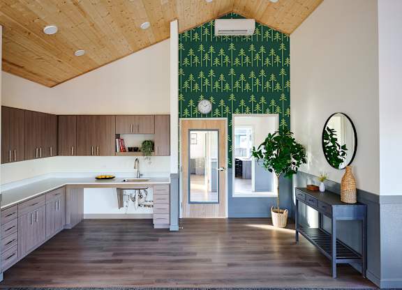 A kitchen with a green patterned wallpaper and wooden cabinets.
