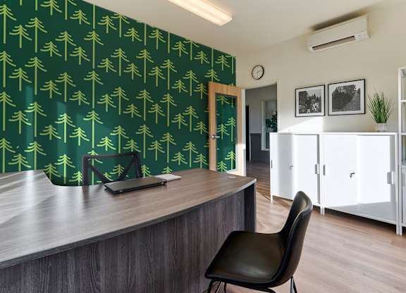 A black chair is in front of a desk with a laptop on it.