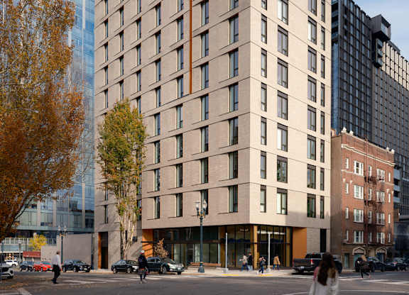 A tall building with many windows is surrounded by trees and other buildings.