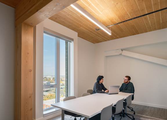 Two people sitting at a table in a room with wooden walls and ceiling.