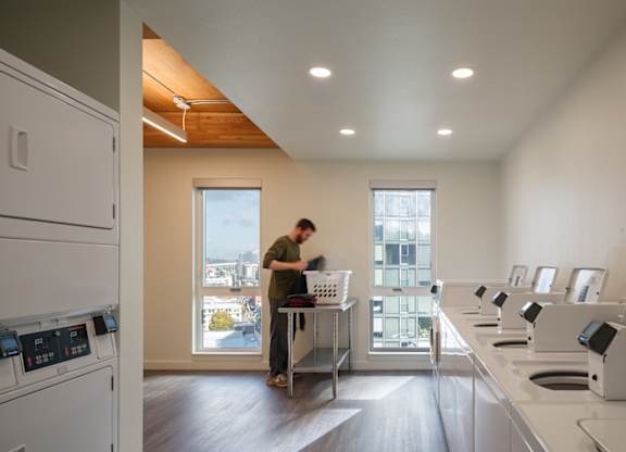 A man is standing in a kitchen with a window behind him.