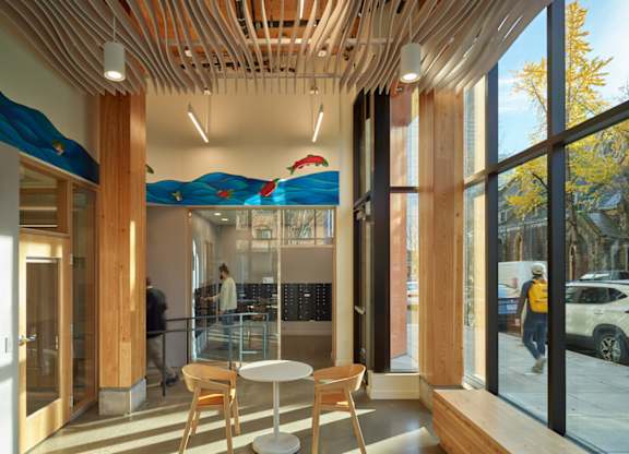 A modern cafe with wooden tables and chairs and a glass wall.