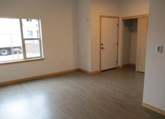 an empty living room with wood floors and a window