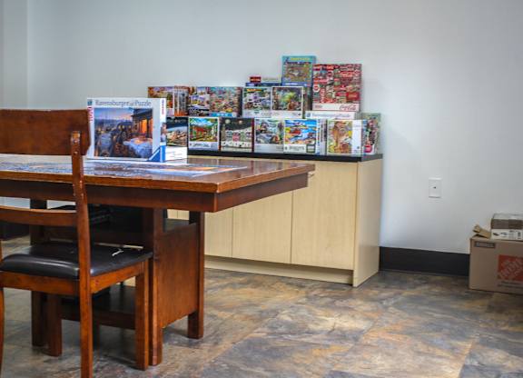 A wooden chair is in front of a table with a book on it.
