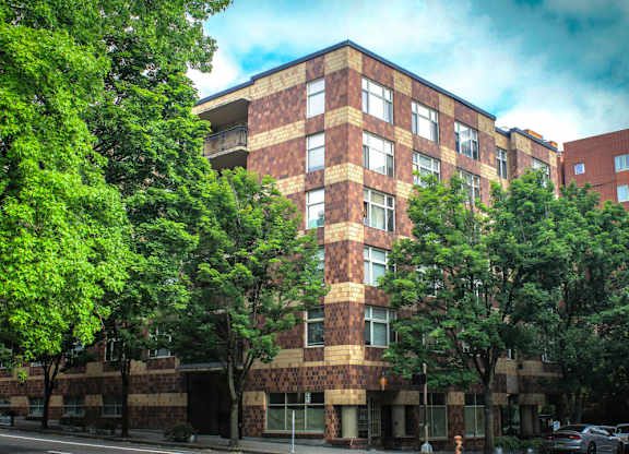 A tall building with a lot of windows and trees in front of it.