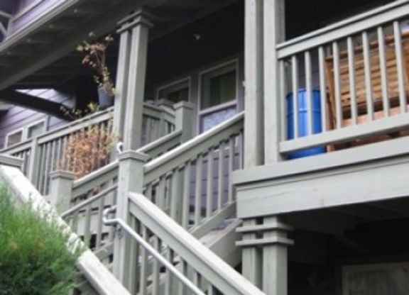 A porch with a white railing and a blue planter.