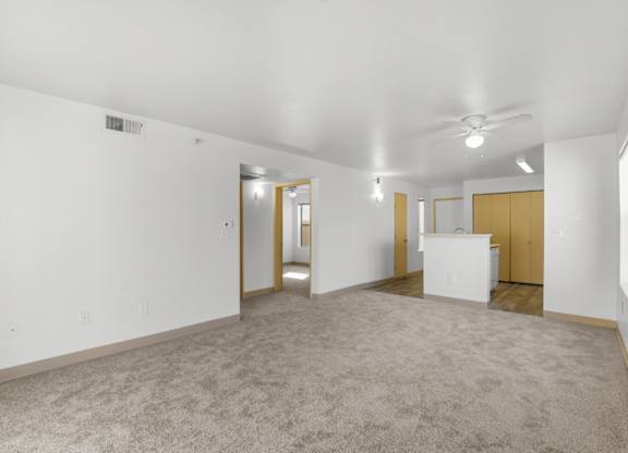 A spacious room with a carpeted floor and a ceiling fan.
