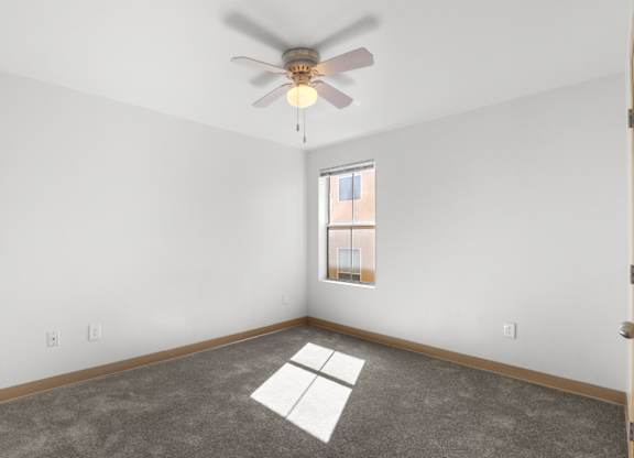 A room with a ceiling fan and a window.
