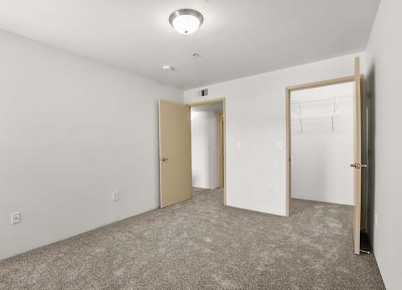 A room with a carpeted floor and three doors.
