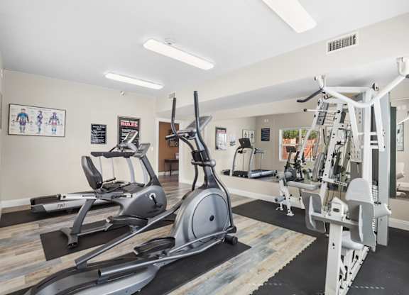 A gym with a variety of equipment including treadmills, elliptical machines, and weight machines.