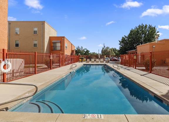 A swimming pool surrounded by orange fencing and buildings.