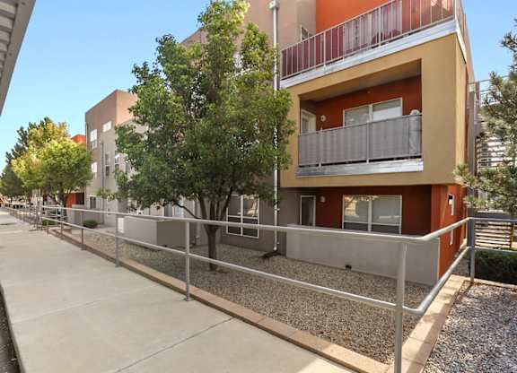 A building with a balcony and a tree in front of it.