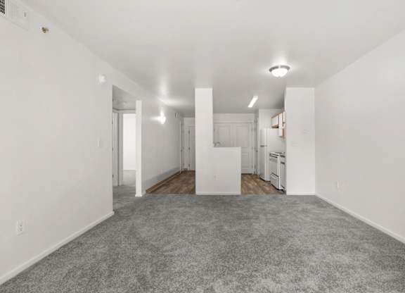 A spacious, empty room with white walls and a grey carpet.