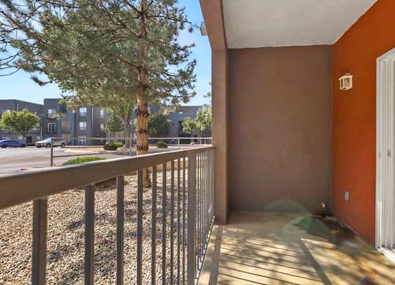 A balcony with a metal railing and a tree in the background.