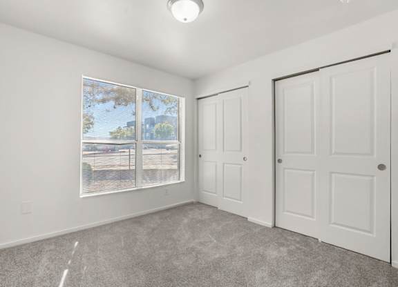 A room with a large window, two doors, and a car parked outside.