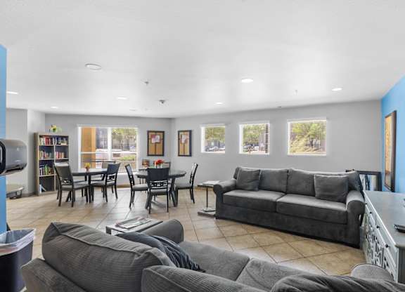 A living room with grey couches and a dining table.