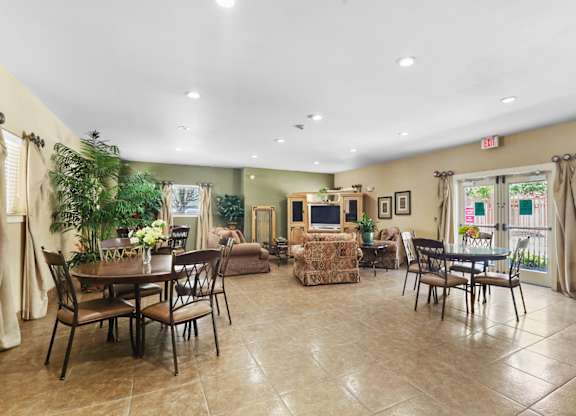 A spacious room with a dining table and chairs, a sofa, and a television.