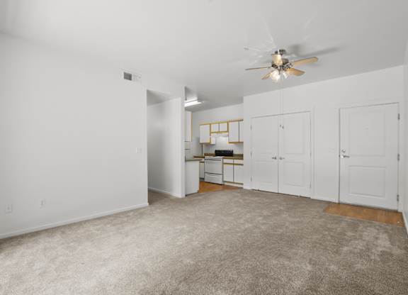 A spacious room with a ceiling fan and a desk with a chair.