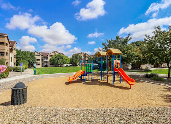 A playground with a yellow slide and a green slide.