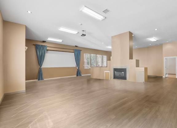 A spacious room with wooden flooring and a fireplace.