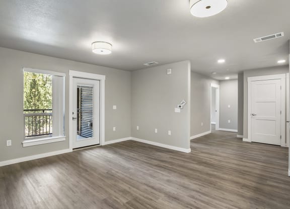 an empty living room with a kitchen in the background