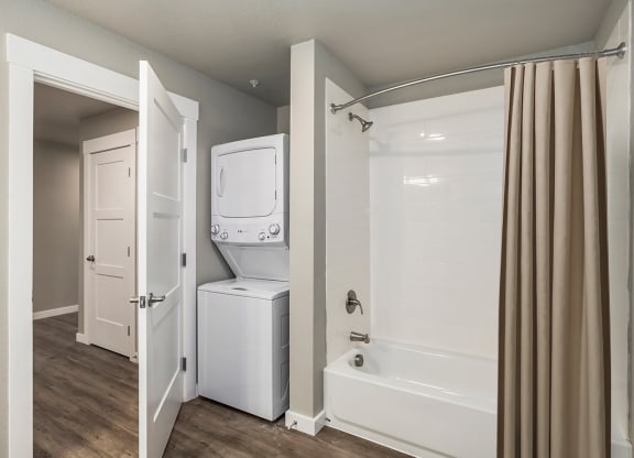 a bathroom with a washer and dryer in it and a shower and tub