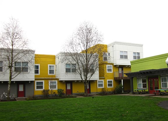a row of colorful houses in front of a green yard